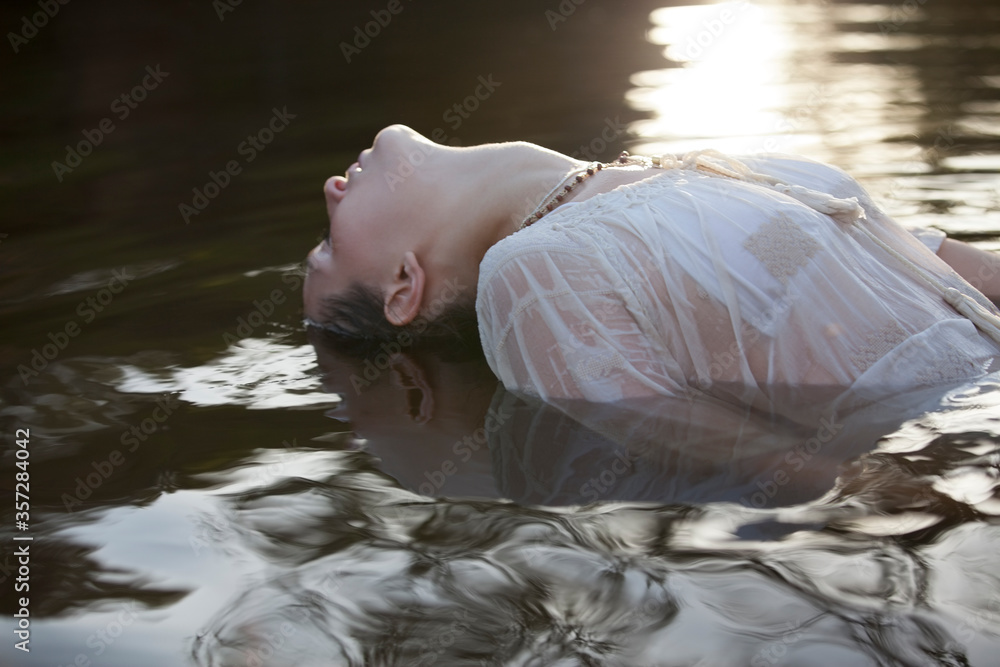 Wall mural Woman leaning head back in river