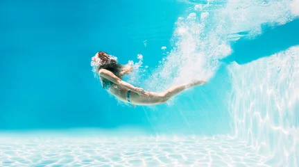 Fotobehang Woman swimming underwater in swimming pool © Robert Daly/KOTO