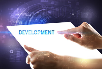 Hand holdig futuristic tablet with DEVELOPMENT inscription, new technology concept