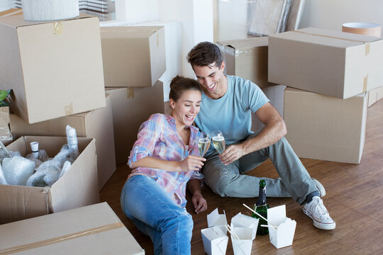 Couple Enjoying Champagne And Chinese Take Out Food In New House