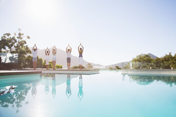 People practicing yoga at poolside
