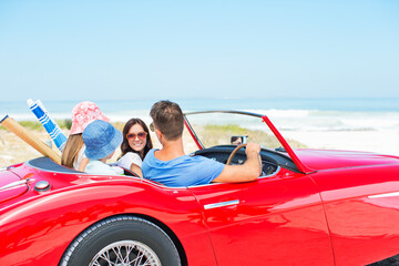 Family driving convertible to beach