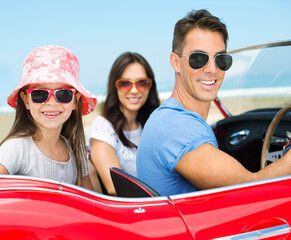 Family driving in convertible on beach