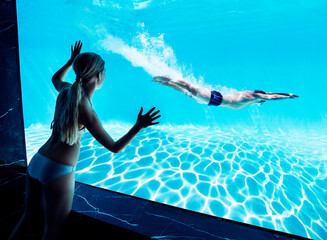 Woman watching boyfriend underwater in swimming pool