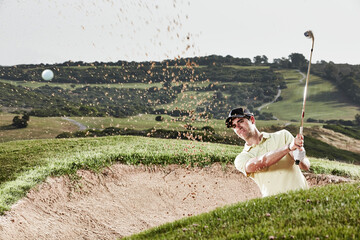 Man swinging from sand trap on golf course