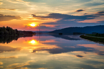 Mirroring of the landscape at sunset on the water surface of the dam. Zilina dam in the north of Slovakia, Europe.