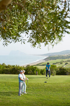 Older Friends Playing Golf On Course