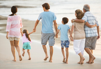 Multi-generation family holding hands on beach