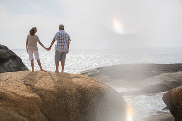 Senior couple holding hands on rocks at beach