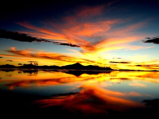 Fototapeta na wymiar Bright red and orange sunset over salt flat in Salar de Uyuni, Bolivia