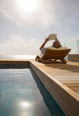 Man reading in lawn chair by pool