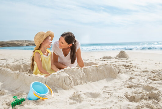 Mother and daughter making sandcastle on beach