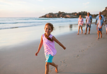 Naklejka premium Girl walking on beach with family in background