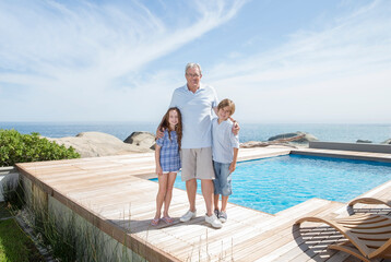 Fototapeta na wymiar Older man and grandchildren smiling by pool