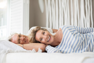 Older couple relaxing together on bed - obrazy, fototapety, plakaty