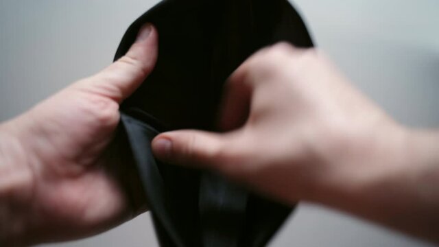 Person holding black leather wallet and opening on white background, empty wallet and no money. Global financial crisis and total unemployment, bankruptcy and debt, people falling into depression