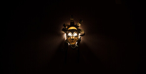 Horror concept. Scary mask with light on the wall inside dark room. Selective focus