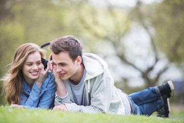Couple listening to headphones in park