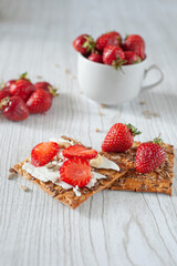 Strawberries in a cup on a light wooden background. Biscuits with cheese, strawberries and hazelnuts. Dietary nutrition. Summer breakfast. A healthy snack.