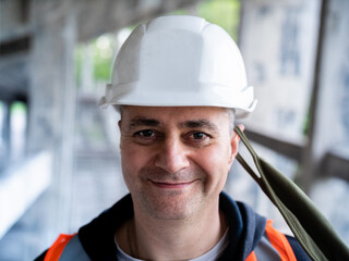 The man removes the protective mask from his face to symbolize the end of the pandemic. Portrait of a male Builder in a construction helmet and a medical antiviral mask.