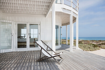 Deck chair on deck overlooking beach - obrazy, fototapety, plakaty