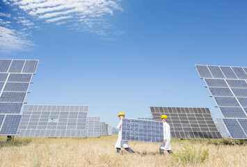 Scientists carrying solar panel in rural landscape