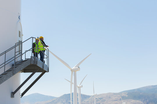 Workers Standing On Wind Turbine In Rural Landscape