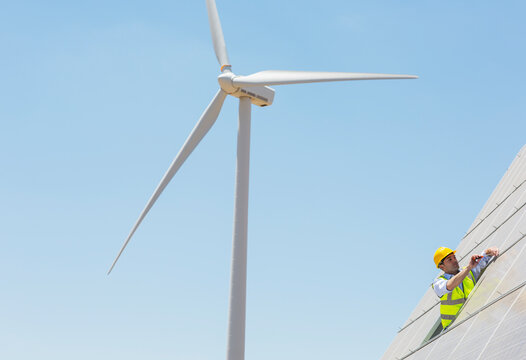 Worker examining solar panel in rural landscape