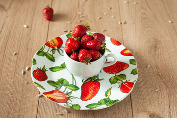Sizabing strawberries in a cup. On a plate with a pattern in the form of strawberries with leaves.