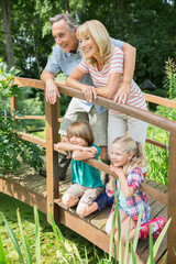 Grandparents and grandchildren smiling on wooden footbridge