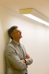 Businessman leaning against office wall
