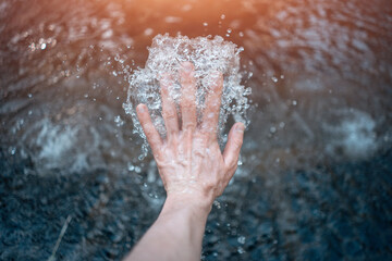 Man's hand touching a natural water source