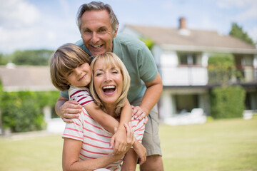 Grandparents and grandson hugging in backyard