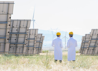 Scientists standing by solar panels in rural landscape