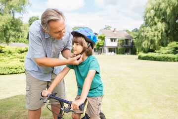 Grandfather adjusting bicycle helmet on grandson