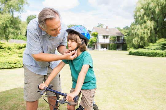 Grandfather adjusting bicycle helmet on grandson