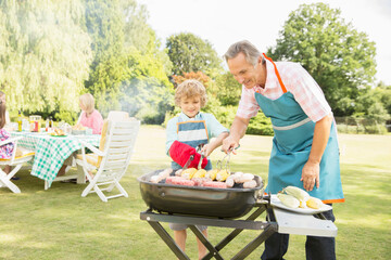 Grandfather and grandson grilling meat and corn on barbecue © Robert Daly/KOTO