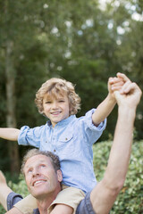 Father carrying son on shoulders outdoors