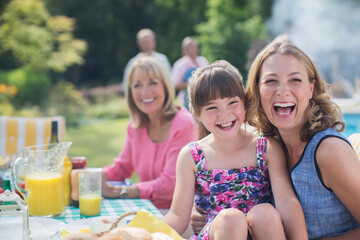 Multi-generation family laughing at table in backyard
