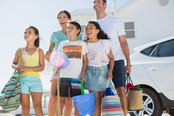 Family standing with beach gear in sunny driveway
