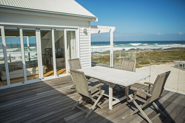 Table and chairs on balcony overlooking beach - obrazy, fototapety, plakaty