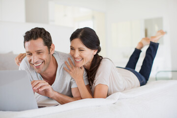 Couple using laptop on bed