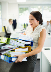 Businesswoman carrying folders in office - obrazy, fototapety, plakaty
