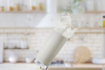 Falling glass with milk in the kitchen