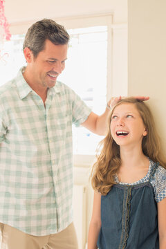 Father measuring daughter's height on wall