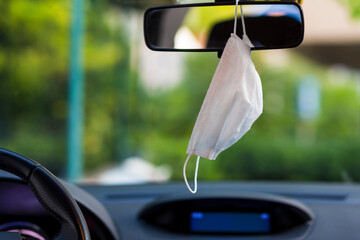 Face mask hung in car's rear-view mirror