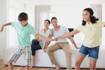 Parents watching daughter and son dancing in living room
