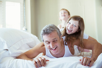 Fototapeta premium Father and children playing on bed