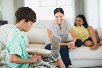 Fototapeta premium Boy using laptop on sofa in living room