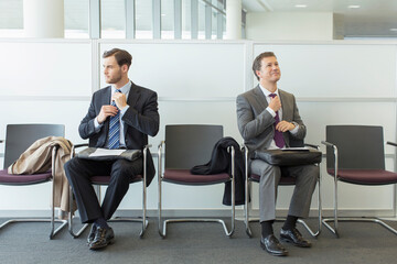 Businessmen adjusting ties in waiting area